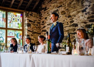 Cris Lowis photo of groom's speech at high table in front of the stained glass window in Llyn Gwynant Big barn
