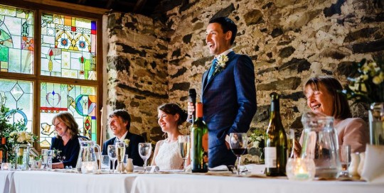 Cris Lowis photo of groom's speech at high table in front of the stained glass window in Llyn Gwynant Big barn